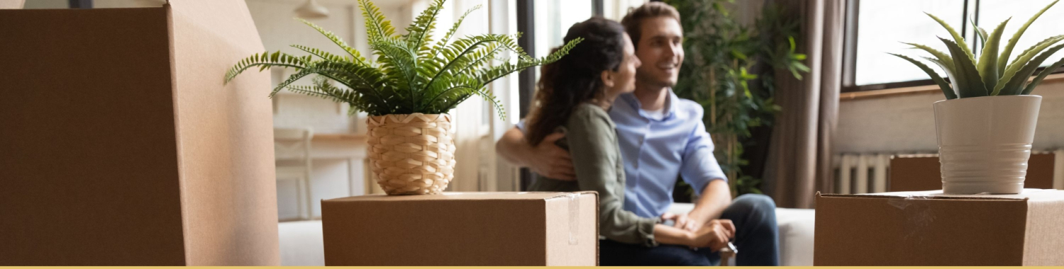 couple sitting on couch with moving boxes all around them